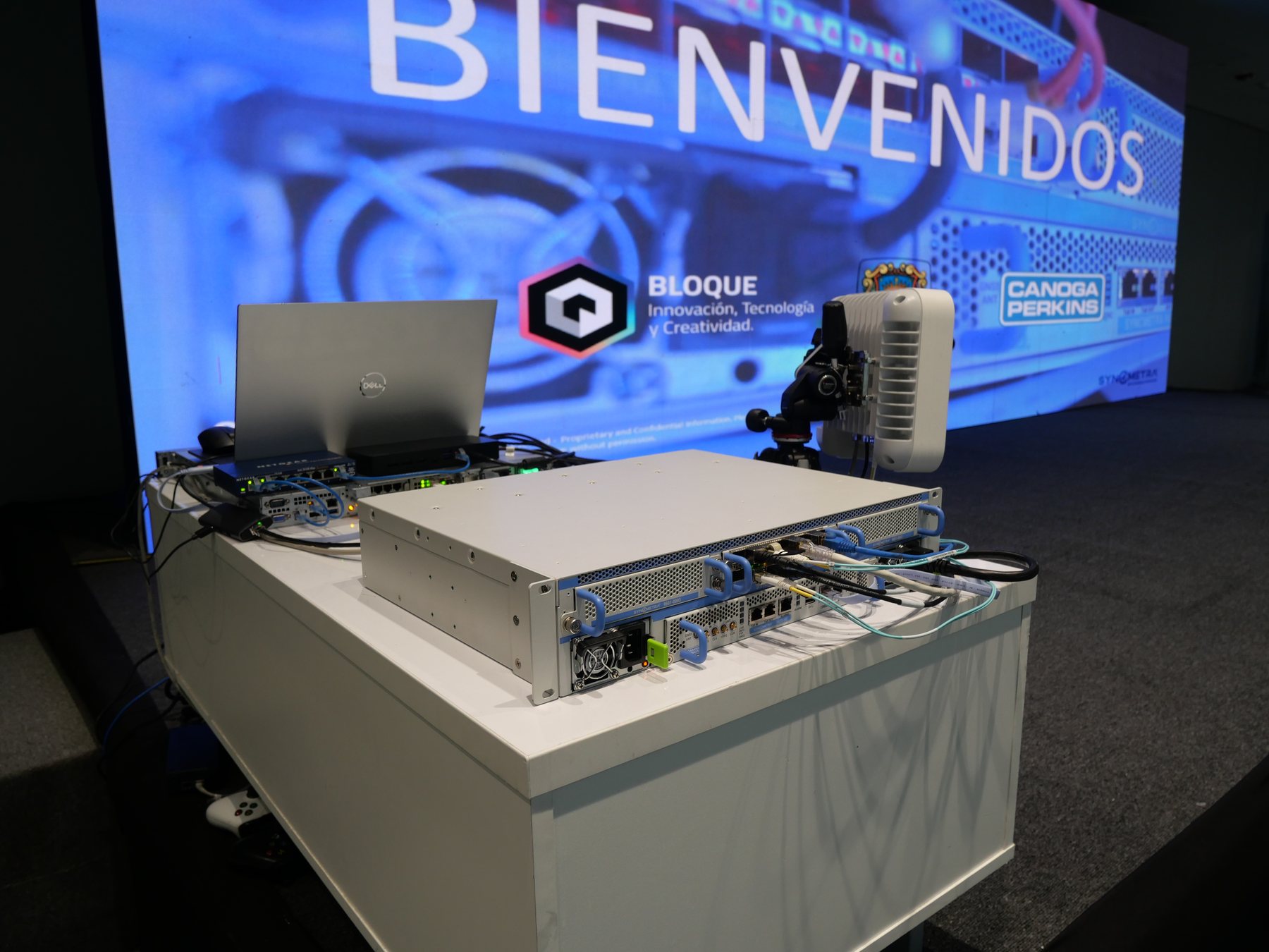 Onstage hardware demo at the SyncMetra LAAM launch — BIENVENIDOS · BLOQUE · CANOGA PERKINS backdrop